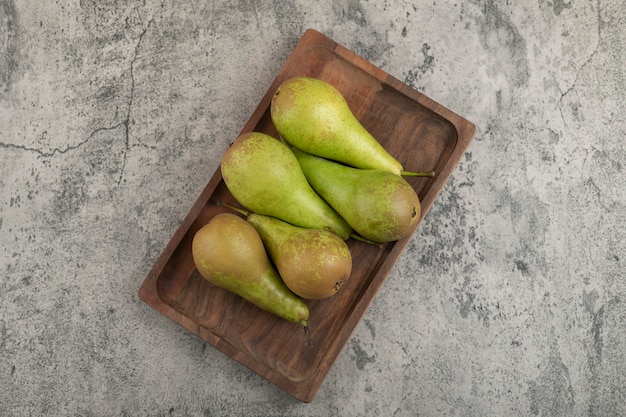 Free photo wooden plate of delicious ripe pears on marble background