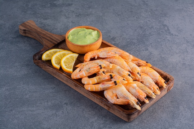 A wooden plate of delicious shrimps on a stone surface