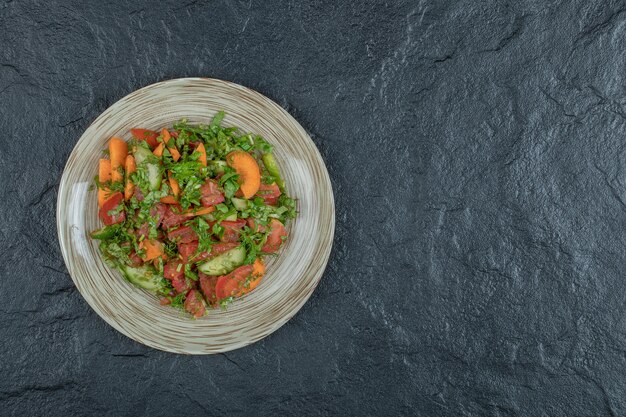 A wooden plate of delicious vegetable salad . 