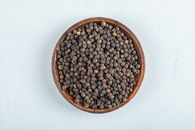 Free photo a wooden plate full of dried pepper on a white background.