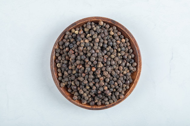 A wooden plate full of dried pepper on a white background. 