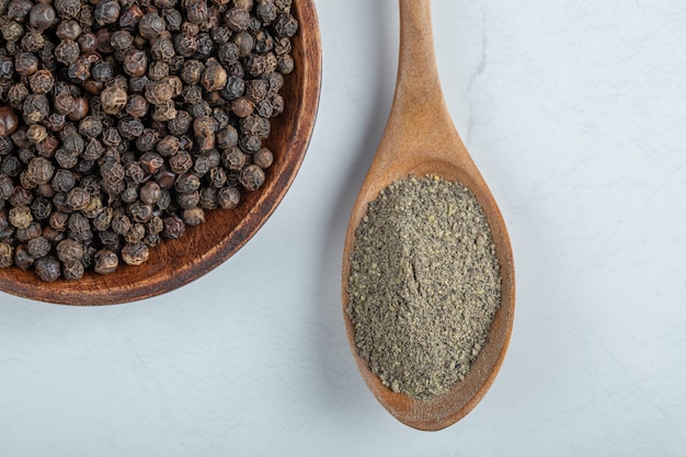 A wooden plate full of dried pepper on a white surface.