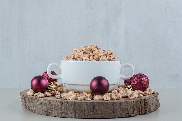 Free photo a wooden plate full of healthy cereals with christmas balls .