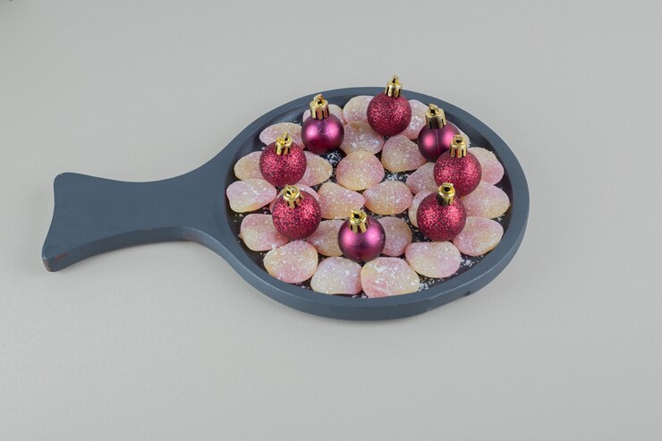 Free Photo a wooden plate full of heart shaped jelly candies with christmas balls .