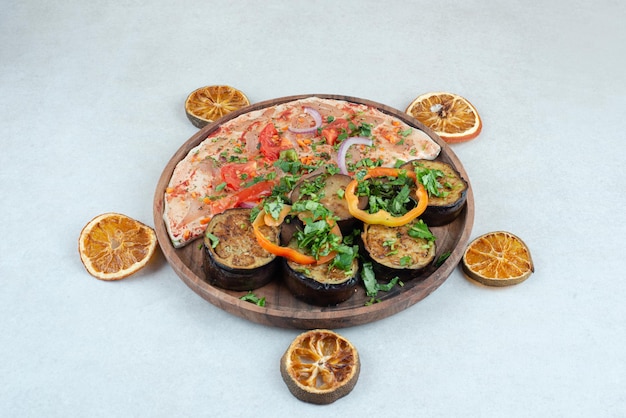 Un piatto di legno pieno di pane pita con melanzane a fette.