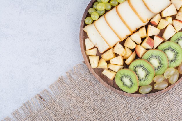 A wooden plate full of sliced fruits and bread