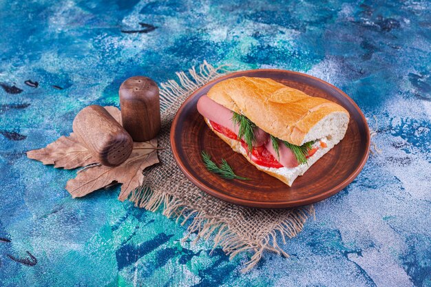 Wooden plate of homemade fresh sandwich on blue surface. 