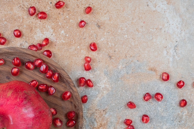 무료 사진 대리석 표면에 신선한 육즙 석류 씨앗의 나무 접시.