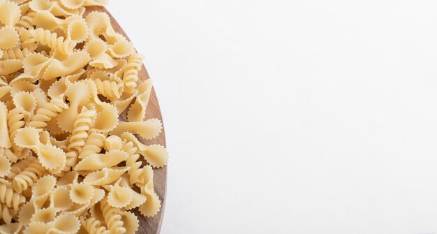 Wooden plate of pasta on white.