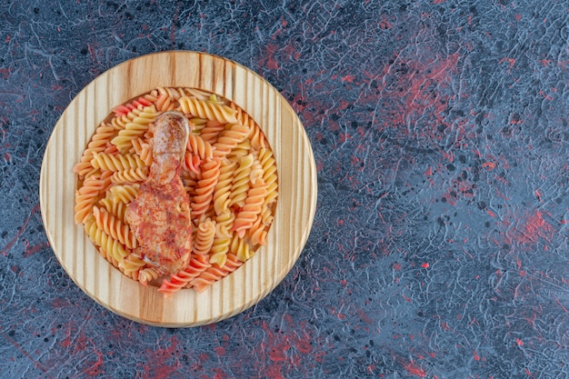 Деревянная тарелка спиральных макарон с мясом куриной ножки