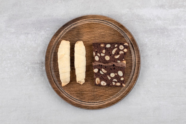 Wooden plate of traditional sweet mutaki and cocoa biscuits on stone table. 