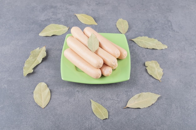 A wooden plate with boiled sausages and bay leaves 