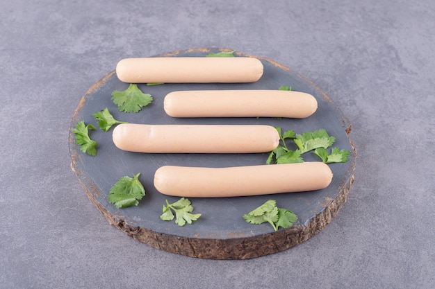 A wooden plate with boiled sausages and parsley 