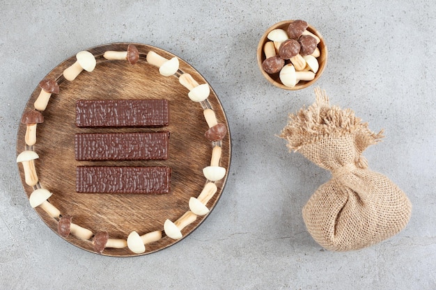 A wooden plate with chocolates and wooden bowl with sweet mushrooms