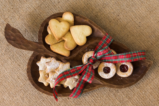 Wooden plate with different cookies on table 