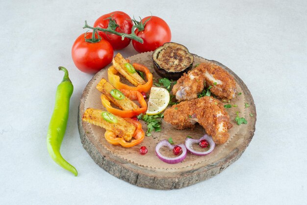 A wooden plate with peppers and tomatoes on white