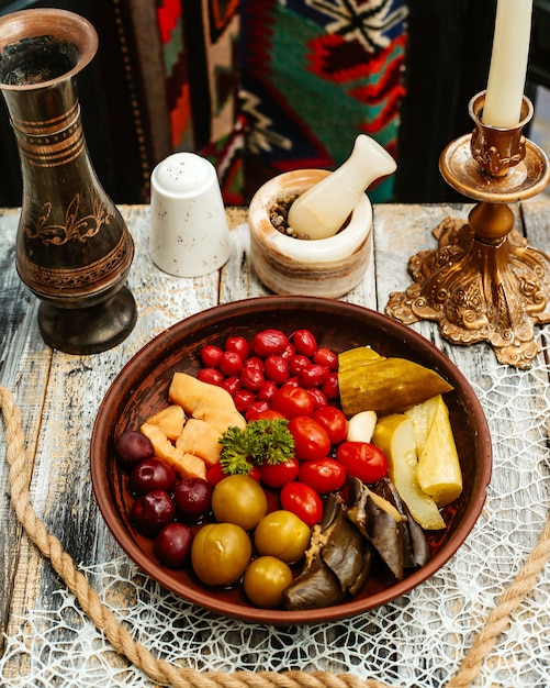 Деревянная тарелка с соленьями на столе