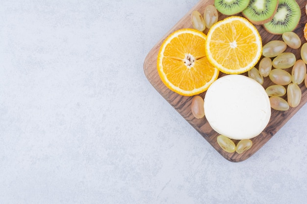 A wooden plate with sliced cheese and fruits. High quality photo