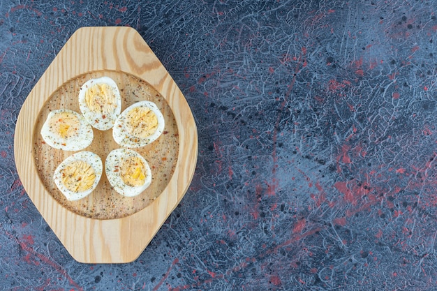 A wooden plate with spices hard boiled eggs . 