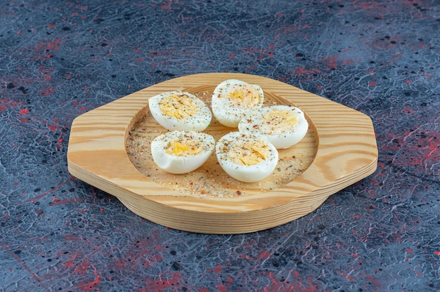 A wooden plate with spices hard boiled eggs . 