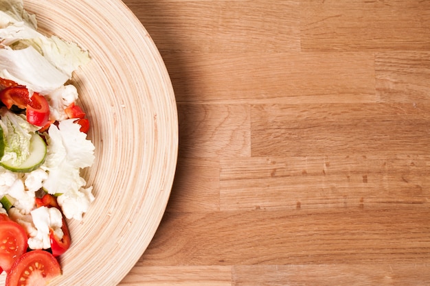 Wooden plate with vegetable salad