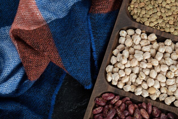 Wooden plates with raw beans on black.