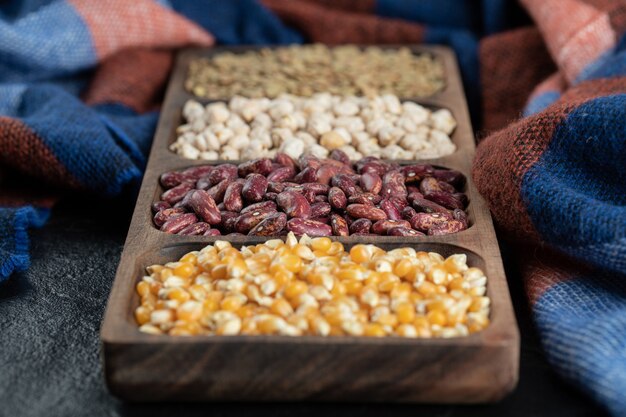 Free photo wooden plates with raw beans and popcorn on a dark