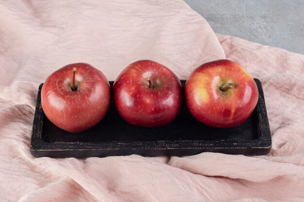 Деревянное блюдо из трех яблок на текстильной поверхности