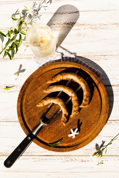 Wooden platter with grilled sausages on fork