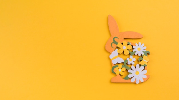 Free photo wooden rabbit with flowers on yellow table