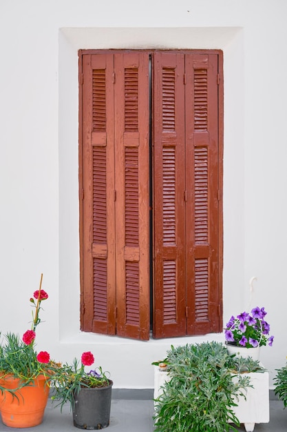 Free photo wooden shutters and flower pots in front of an old traditional house in the city of lindos on the island of rhodes the greek islands of the dodecanese archipelago a popular tourism destination