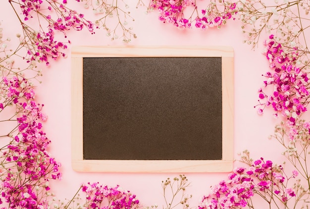 Wooden slate decorated with baby's-breath flowers on pink background