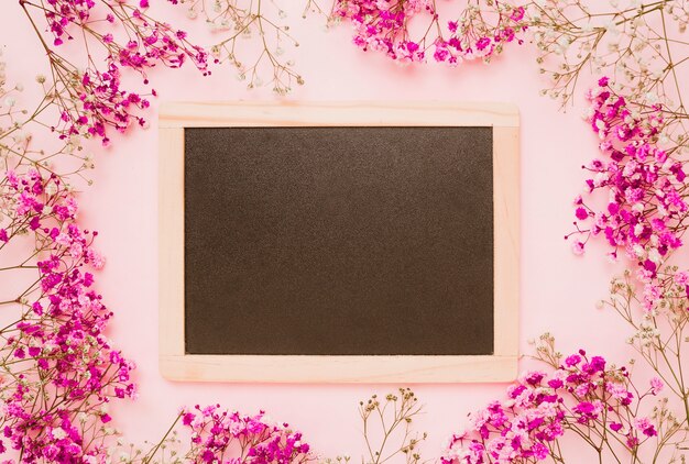 Wooden slate decorated with baby's-breath flowers on pink background