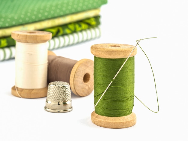 糸刺繍の木のスプールは白い背景の上の布で設定