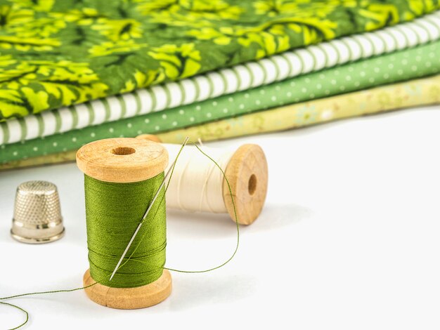 Wooden spool of thread embroidery set with cloth over white background