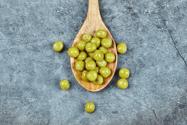 A wooden spoon of boiled green peas.