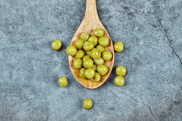 A wooden spoon of boiled green peas.