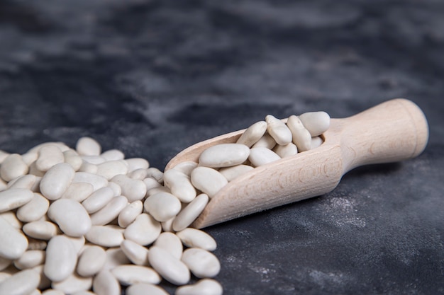 A wooden spoon full of dry butter beans placed on stone