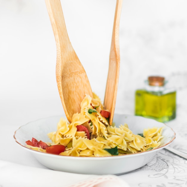 Wooden spoon and spatula in the cooked serving farfalle pasta