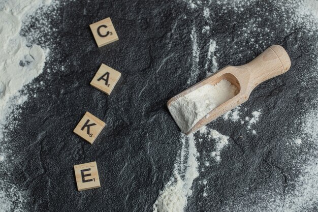 A wooden spoon with flour and wooden letters .