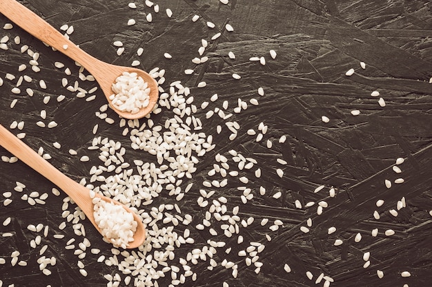 Wooden spoon with rice grains on textured background