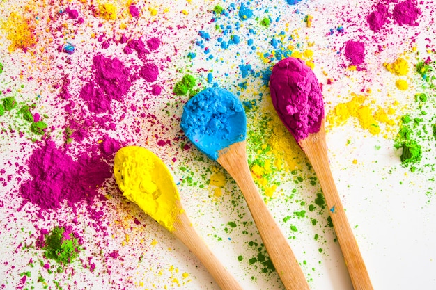 Free photo wooden spoon with yellow; blue and pink color powder