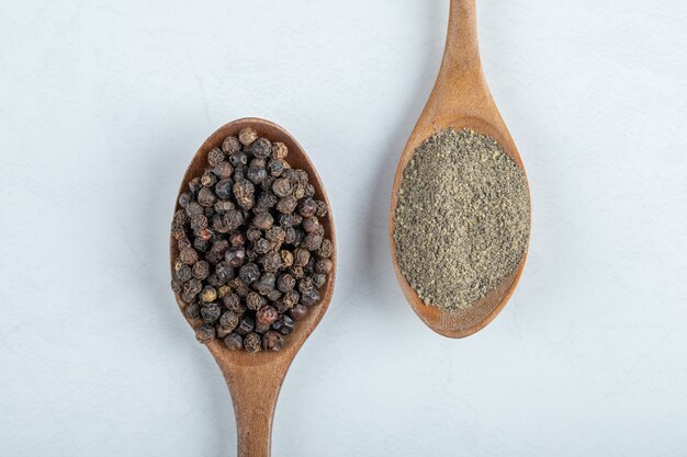 Wooden spoons full of dried pepper on a white background. 