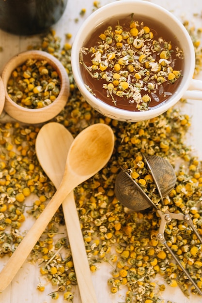 Wooden spoons and strainer near chamomile tea