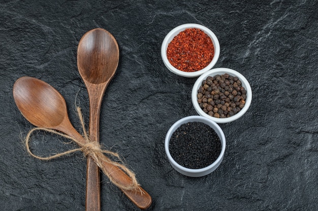 Free photo wooden spoons and various spices on a dark surface.