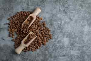 Free photo wooden spoons with coffee beans on a gray background.