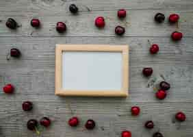 Free photo wooden surface with blank frame and cherries