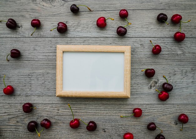 Wooden surface with blank frame and cherries