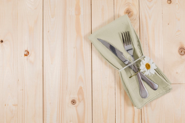 Wooden surface with cutlery and cute daisy