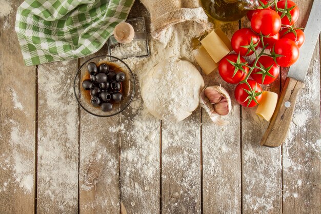 Wooden surface with flour and ingredients for cooking pasta